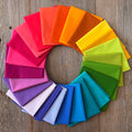Alchemy Rainbow Fat Quarter Bundle arranged in a circular pattern on a wooden surface